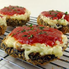 four mini cakes with sauce and cheese on top are sitting on a cooling rack, ready to be eaten