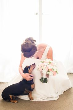 the bride and her dog are sitting on the floor in front of the window with white curtains