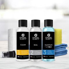 three different types of cleaning products sitting on a table next to towels and sponges