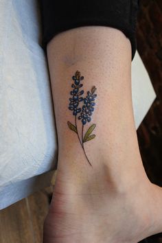 a small tattoo on the ankle of a woman's foot, with blue flowers