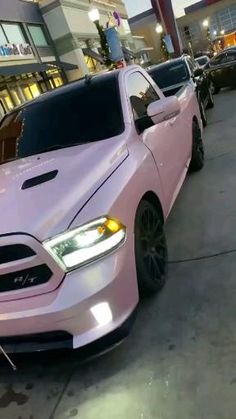 a pink truck parked in front of a building next to other cars on the street