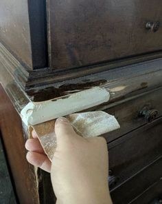 someone is peeling paint off the side of an old dresser with a rag on it