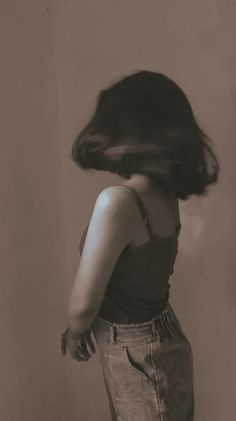 a woman standing in front of a toilet with her hair blowing back to the side