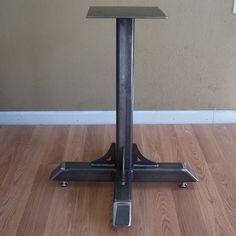 a square metal table sitting on top of a hard wood floor next to a wall