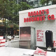 there is a doughnut shop with red lettering on the front and white brick walls