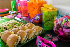 a table topped with lots of sandwiches and candy bar items on top of green trays