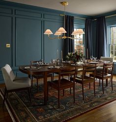 a dining room with blue walls and wooden flooring has a rug on the floor