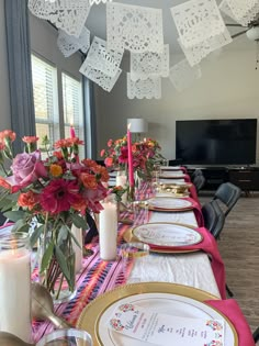 the table is set with place settings and flowers in vases, candles, and napkins