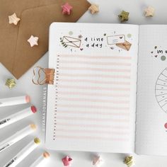 an open planner book sitting on top of a table next to pencils and paper