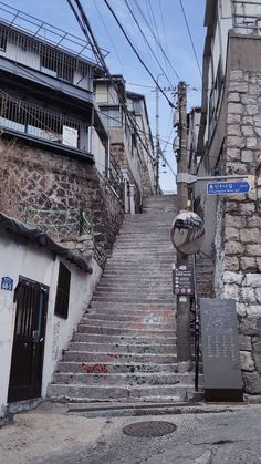 an alleyway with stone steps and graffiti on the walls, next to a street sign