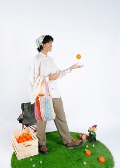 a man standing on top of a green patch of grass holding an orange in his hand