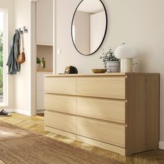 an empty room with a dresser, mirror and coat rack on the wall next to it