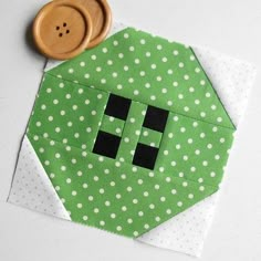 a close up of a piece of fabric with a button on it and a green hexagon