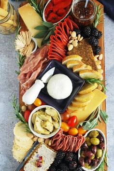 an assortment of cheeses, meats and vegetables on a platter with olives