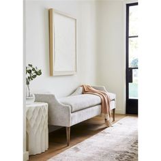 a white couch sitting in front of a window on top of a wooden floor next to a rug