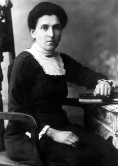 an old black and white photo of a woman sitting at a table