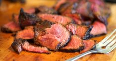 some meat is sitting on a cutting board with a fork