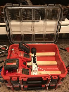 an open tool box with tools in it sitting on the floor next to some wires