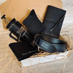 a black leather belt and some other items in a box on a wooden table with straw