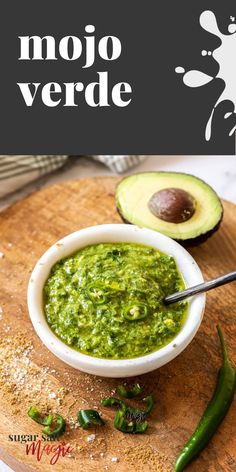 an avocado sauce in a white bowl on a wooden cutting board next to sliced green peppers