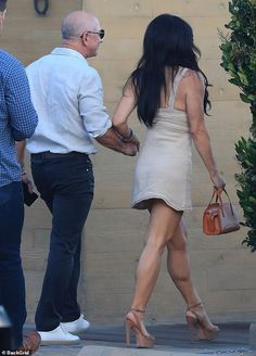 the woman is walking down the street with her hand in her other hand as she holds onto another man's purse