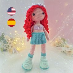 a crocheted doll with red hair standing in front of a christmas tree and decorations