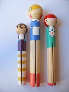 three wooden peg dolls sitting next to each other