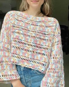 a woman is wearing a crocheted sweater and jeans