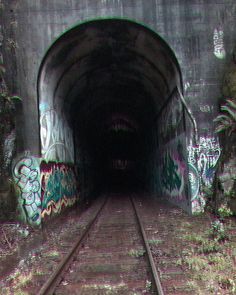 a train track going into a tunnel with graffiti on it