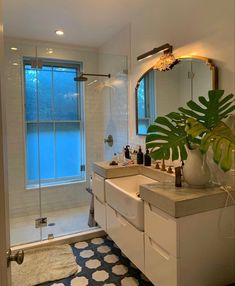 a bathroom with a sink, mirror and shower stall in it's corner next to a large potted plant