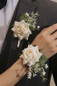 two white roses are attached to the lapel of a man in a tuxedo