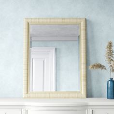 a white dresser with a blue vase and mirror