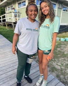 two girls standing on a wooden deck in front of a house