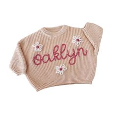 a pink sweater with flowers on it that says,'baby'in red and white