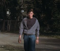 a young man standing in the middle of a road with his foot on a skateboard