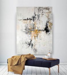 an abstract painting hangs on the wall next to a blue bench with a blanket draped over it