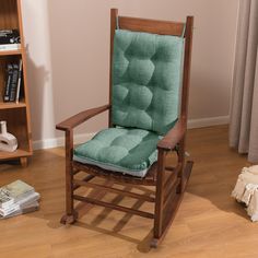 a wooden rocking chair with a green cushion on top of it in front of a bookshelf