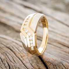 a yellow gold ring with diamonds on it sitting on a piece of wooden planks