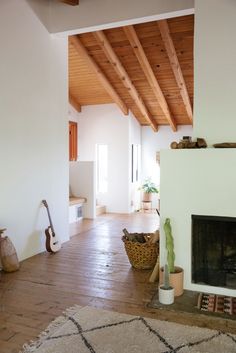 an empty living room with a fireplace and wooden beams on the ceiling is seen in this image