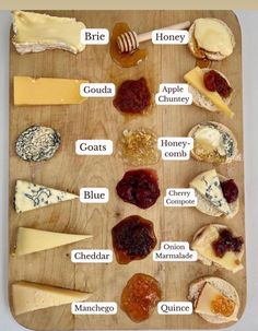 a wooden cutting board topped with lots of different types of cheeses and jams