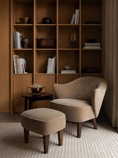 a chair and ottoman in front of a bookshelf