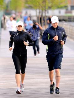 a man and woman running on a boardwalk