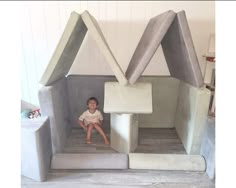 a little boy sitting in a fake house made to look like an airy building