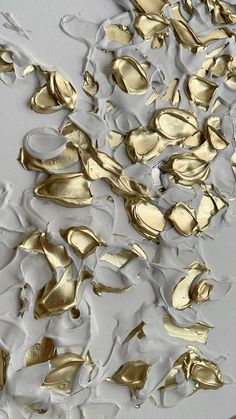 an abstract painting with gold and white paint on it's surface, as well as leaves