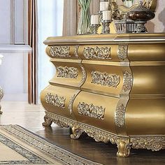 an ornately decorated gold chest of drawers in a living room with rugs and vases on the floor