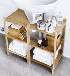 a wooden shelf with towels, soaps and other personal care items on it in front of a sink