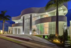 a large white building with palm trees in front of it at night, lit up by street lights