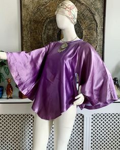 💜 Beautiful vintage late 1960s to early 1970s purple slippery satin tunic top.  Features wide angel sleeves, A-line shape, rounded front and back bottom hem, boat neckline finished with purple velvet. Handmade to a very good standard 💜 💜 There is a very faint area of colour variation on the front but it's so faint you really have to look hard to see it. This does not detract from the beauty of this garment though 💜  💜Fits sizes XS-Small. Best for bust up to 34 inches (18 inches across seam to seam). Length approximately 30 inches shoulder to longest point at hem 💜  Bust: best for up to 34 inches Length: 30 inches approx. shoulder to bottom hem ANY ACCESSORIES SHOWN IN THE PHOTOS ARE NOT INCLUDED IN THE SALE UNLESS OTHERWISE STATED. ♡ Facebook: https://www.facebook.com/VicAndBertieVin Purple Satin Top For Spring, Spring Purple Satin Top, Purple Silk Party Tops, Purple Satin Party Top, Purple Silk Evening Top, Purple Bohemian Party Tops, Purple Bohemian Top For Party, Satin Tunic, Angel Sleeve