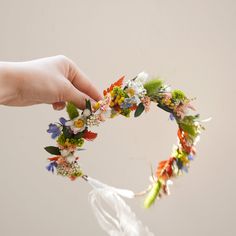 a person is holding a flower crown in their hand and it looks like they are making something out of flowers