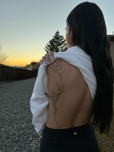 the back of a woman's body with a flower tattoo on her left shoulder